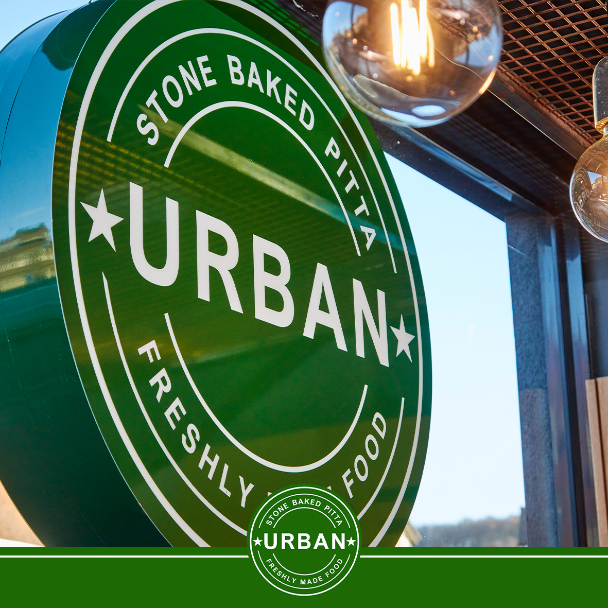 The round green Urban Pitta sign above one of our shops